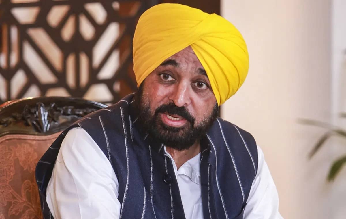 एक आदमी ने सफेद शर्ट पहनी हुई है और वह कैमरे की तरफ देख रहा है।